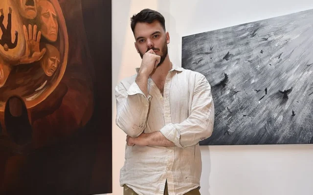 L'ex-otage Andrey Kozlov pose à New York en mai 2025 avec l'œuvre d'art qu'il a créée au cours des derniers mois. (Crédit : autorisation)