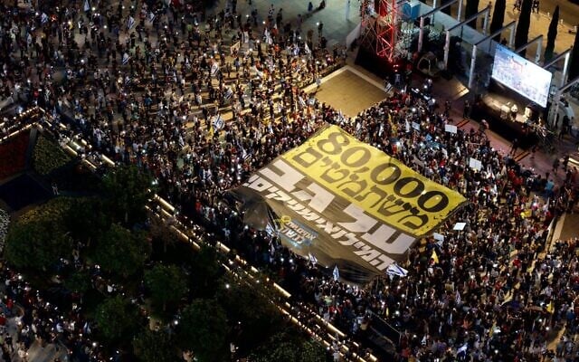 Des manifestants anti-gouvernement tenant une banderole sur laquelle on peut lire « 80 000 personnes se soustraient à leur devoir et profitent des réservistes », sur la Place Habima, à Tel Aviv, le 24 mai 2025. (OM/Mouvement de protestation pour la démocratie)