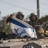 Illustration : Des soldats brandissent un drapeau israélien sur un char près de la frontière avec le Liban, le 14 octobre 2023. (Crédit : AP Photo/Petros Giannakouris)