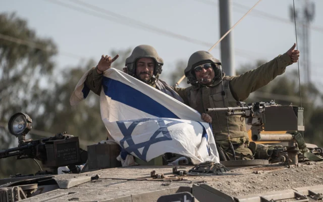 Illustration : Des soldats brandissent un drapeau israélien sur un char près de la frontière avec le Liban, le 14 octobre 2023. (Crédit : AP Photo/Petros Giannakouris)