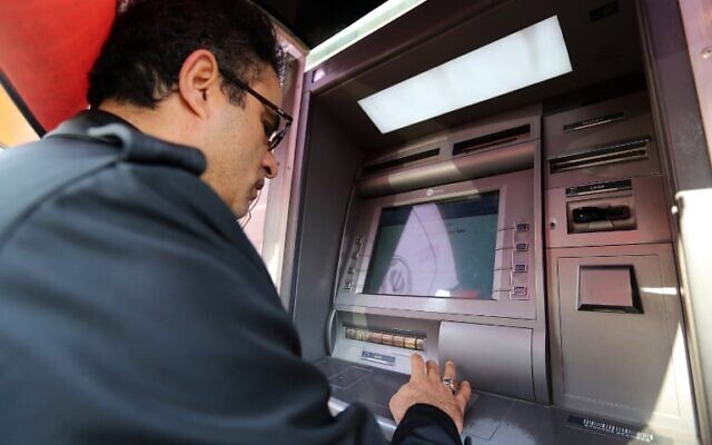 Un Iranien retirant de l'argent à un distributeur automatique de la banque Sepah, dans la capitale Téhéran, le 19 janvier 2016. (Crédit : Atta Kenare/AFP) Un Iranien retirant de l'argent à un distributeur automatique de la banque Sepah, dans la capitale Téhéran, le 19 janvier 2016. (Crédit : Atta Kenare/AFP)
