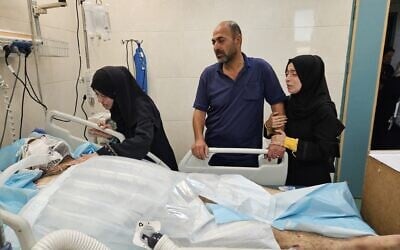 La médecin palestinienne Alaa al-Najjar rendant visite à son mari blessé dans l'unité de soins intensifs de l'hôpital Nasser à Khan Younès, dans la bande de Gaza, après qu'une frappe aérienne israélienne aurait touché leur domicile. Al-Najjar aurait perdu 9 de ses 10 enfants dans l'attaque, qui s'est produite peu après son départ pour le travail. (Crédit : Hani Alshaer/Anadolu via Reuters)