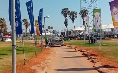 Un employé municipal retire les drapeaux de ce qui aurait dû être le centre névralgique de la marche des Fiertés de Tel Aviv, dans le parc Charles Clore, le long de la plage, le 13 juin 2025. (Crédit : Noam Lehmann/Le Times of Israel)