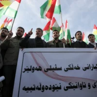 Des manifestants, au lendemain de frappes de missiles lancées par les Gardiens de la révolution iraniens sur plusieurs sites de la ville, brandissent une bannière et des drapeaux kurdes devant le bureau des Nations unies à Erbil, dans la région autonome kurde d’Irak, le 16 janvier 2024. (Crédit : Safin HAMID / AFP)