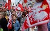 Des partisans du candidat à la présidence polonaise Karol Nawrocki brandissant des drapeaux polonais alors qu'ils se rassemblent pour assister à un meeting électoral, à Varsovie, une semaine avant le second tour des élections présidentielles, le 25 mai 2025. (Crédit :  Wojtek Radwanski/AFP)