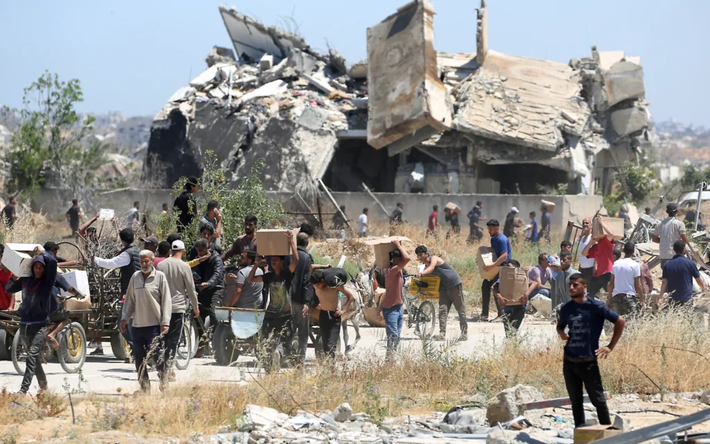 Des personnes transportent des caisses de fournitures de secours obtenues auprès de la Fondation humanitaire de Gaza, dans le centre de la bande, le 29 mai 2025. (Crédit : Eyad BABA / AFP)