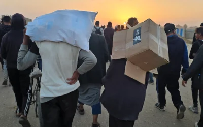 Un jeune portant une boîte vide de fournitures humanitaires provenant de la Gaza Humanitarian Foundation, tandis que des Palestiniens déplacés marchent près d'un centre de distribution alimentaire, à Rafah, dans le sud de la bande de Gaza, le 1ᵉʳ juin 2025. (Crédit : AFP)
