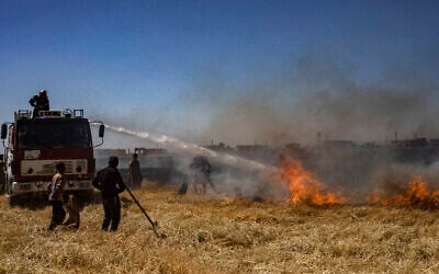 Syrian firefighters use water cannon to extinguish a fire in a wheat field outside Qamishli in northeastern Syria, on June 2, 2025. (Photo by Delil SOULEIMAN / AFP)