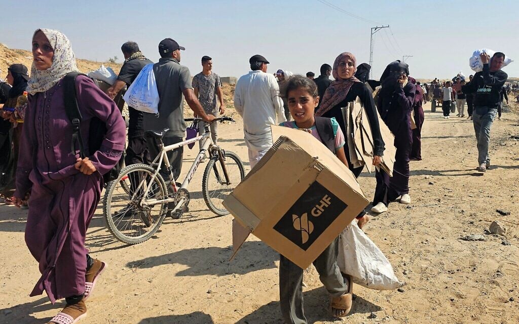 Des Palestiniens marchent le long d'une route pour recevoir des colis d'aide humanitaire de la Fondation humanitaire de Gaza, soutenue par les États-Unis, à Rafah, dans le sud de la bande de Gaza, le 5 juin 2025. (Crédit : AFP)