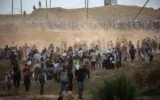 Des membres d'une société de sécurité privée américaine, engagés par la Gaza Humanitarian Foundation (GHF), dirigeant les Gazaouis déplacés qui se rassemblent pour recevoir des secours dans un centre de distribution dans le centre de la bande de Gaza, le 8 juin 2025. (Crédit : Eyad Baba/AFP)