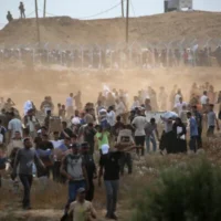 Le 8 juin 2025, des membres d'une société de sécurité privée américaine, sous contrat avec la Fondation humanitaire pour Gaza (GHF), dirigent des Palestiniens déplacés alors qu'ils se rassemblent pour recevoir de l'aide d'urgence dans un centre de distribution du centre de la bande de Gaza. (Crédit : Eyad BABA / AFP)
