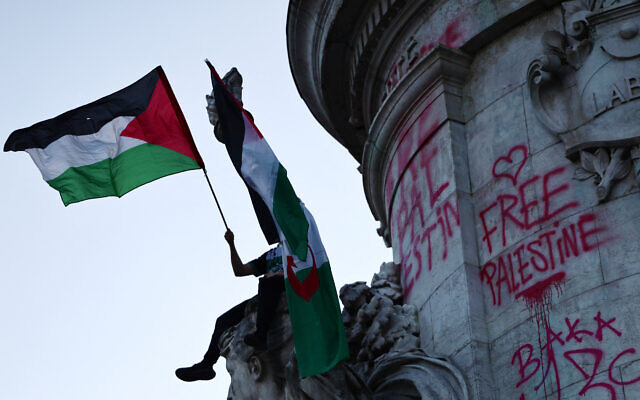 Un manifestant brandissant un drapeau palestinien sur le Monument de la République lors d'un rassemblement en soutien à l'eurodéputée du parti LFI, Rima Hassan lors d'un rassemblement en soutien à Rima sur la place de la République à Paris, le 12 juin 2025. (Crédit : Thibaud Moritz/AFP)