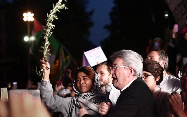 Le fondateur du parti français de gauche radicale La France Insoumise (LFI), Jean-Luc Mélenchon (à droite), s'exprimant aux côtés de l'eurodéputée du parti LFI, Rima Hassan (à gauche), tenant un rameau d'olivier, lors d'un rassemblement en soutien à Rima sur la place de la République à Paris, le 12 juin 2025. (Crédit : Thibaud Moritz/AFP)
