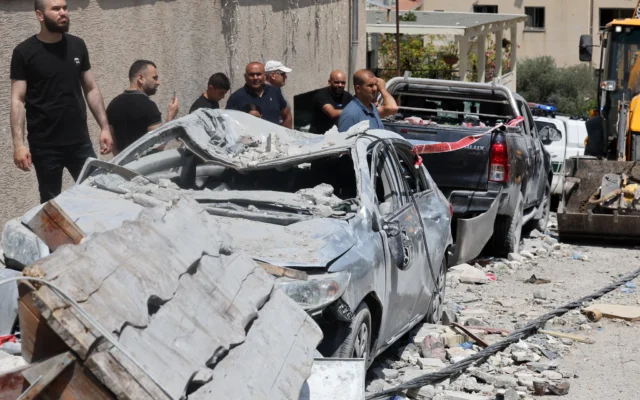 Des habitants se tiennent près de voitures endommagées dans la ville de Tamra, dans le nord d'Israël, suite à une attaque à la roquette de l'Iran, le 15 juin 2025. (Crédit : Ahmad GHARABLI / AFP) Des habitants se tiennent près de voitures endommagées dans la ville de Tamra, dans le nord d'Israël, suite à une attaque à la roquette de l'Iran, le 15 juin 2025. (Crédit : Ahmad GHARABLI / AFP)