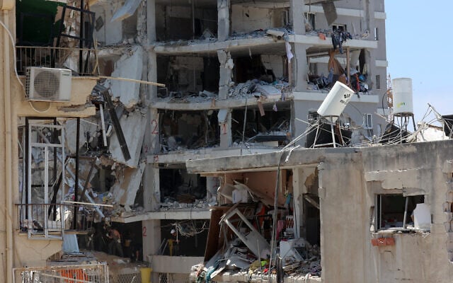 Les secours israéliens et les soldats se tiennent au milieu des décombres de bâtiments fortement endommagés, après une frappe de missiles iraniens dans la nuit du 15 juin 2025, à Bat Yam. (Crédit :   GIL COHEN-MAGEN / AFP)