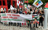 L'actrice française Corinne Masiero (3e à droite) se tient derrière une banderole avant de participer à une marche à Paris le 15 juin 2025, organisée par des syndicats et associations français à partir de La Villette, dans le 19e arrondissement de la capitale française, jusqu'à Bruxelles, afin de « faire pression sur les autorités européennes pour qu'elles imposent des sanctions contre Israël » et mettre fin au « massacre » à Gaza. (Crédit : Thomas SAMSON / AFP)