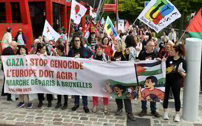 L'actrice française Corinne Masiero (3e à droite) se tient derrière une banderole avant de participer à une marche à Paris le 15 juin 2025, organisée par des syndicats et associations français à partir de La Villette, dans le 19e arrondissement de la capitale française, jusqu'à Bruxelles, afin de « faire pression sur les autorités européennes pour qu'elles imposent des sanctions contre Israël » et mettre fin au « massacre » à Gaza. (Crédit : Thomas SAMSON / AFP)
