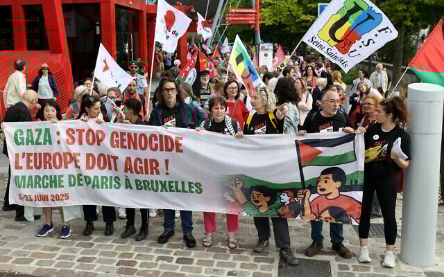 L'actrice française Corinne Masiero (3e à droite) se tient derrière une banderole avant de participer à une marche à Paris le 15 juin 2025, organisée par des syndicats et associations français à partir de La Villette, dans le 19e arrondissement de la capitale française, jusqu'à Bruxelles, afin de « faire pression sur les autorités européennes pour qu'elles imposent des sanctions contre Israël » et mettre fin au « massacre » à Gaza. (Crédit : Thomas SAMSON / AFP)