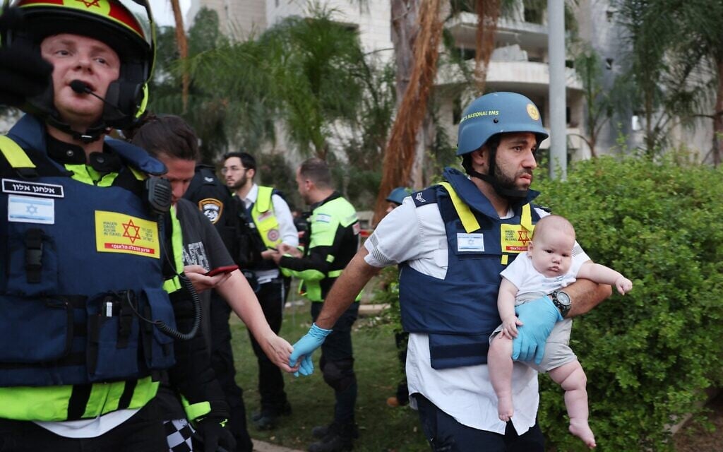 Un secouriste portant un bébé près d'un bâtiment endommagé à la suite d'une frappe de missile iranien dans la ville israélienne de Petah Tikva, à l'est de Tel Aviv, le 16 juin 2025. (Crédit : Jack Guez/AFP)