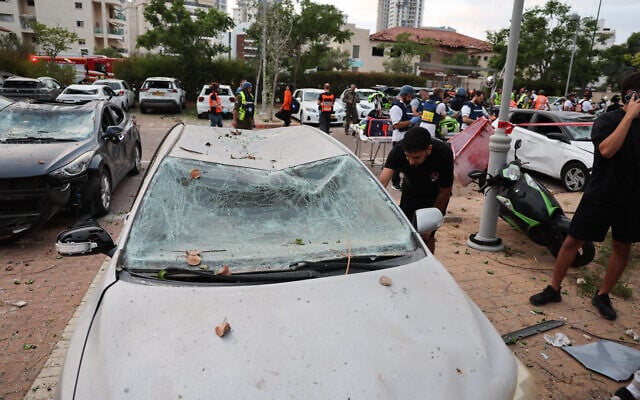 Un homme inspectant une voiture endommagée après un tir de missile iranien dans la ville israélienne de Petah Tikva, à l'est de Tel Aviv, le 16 juin 2025. (Crédit : Jack Guez/AFP)
