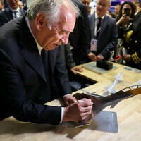 Le Premier ministre français François Bayrou signe une maquette d'un avion de combat Rafale lors de la 55e édition du Salon international de l'aéronautique et de l'espace au parc des expositions du Bourget, à Paris, le 16 juin 2025. (Crédit : ALAIN JOCARD / POOL / AFP)