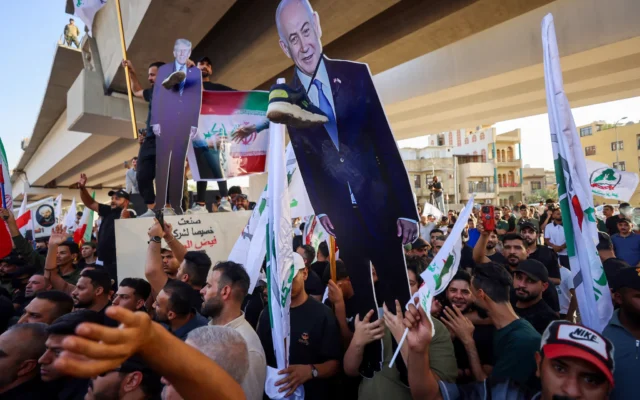 Des partisans de groupes irakiens pro-Iran brandissant une photo du président américain Donald Trump et du Premier ministre Benjamin Netanyahu lors d'une manifestation à Bagdad en soutien à l'Iran, le 16 juin 2025. (Crédit : Ahmad al-Rubaye/AFP)