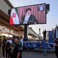 Des partisans de groupes terroristes irakiens pro-Iran transportant un écran sur lequel apparaît le guide suprême iranien, l'ayatollah Ali Khamenei, lors d'une manifestation à Bagdad près de la zone verte, le quartier ultra-sécurisé où se trouve l'ambassade américaine, le 16 juin 2025. (Crédit : Ahmad al-Rubaye/AFP)