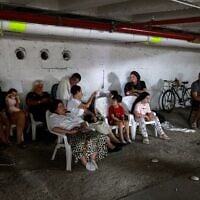 Des personnes réfugiées dans un parking lors d'une nouvelle salve de roquettes iraniennes, à Tel Aviv, le 17 juin 2025. (Crédit : Menahem Kahana/AFP)