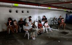 Des personnes réfugiées dans un parking lors d'une nouvelle salve de roquettes iraniennes, à Tel Aviv, le 17 juin 2025. (Crédit : Menahem Kahana/AFP)