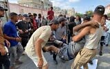 Des Palestiniens évacuant un homme qui aurait été blessé par des tirs israéliens alors qu'il attendait près d'un centre d'aide alimentaire à l'hôpital Nasser de Khan Younès, dans le sud de la bande de Gaza, le 17 juin 2025. (Crédit : AFP)