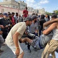 Des Palestiniens évacuant un homme qui aurait été blessé par des tirs israéliens alors qu'il attendait près d'un centre d'aide alimentaire à l'hôpital Nasser de Khan Younès, dans le sud de la bande de Gaza, le 17 juin 2025. (Crédit : AFP)