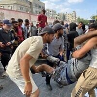 Des Palestiniens evacuant un homme qui aurait été blessé par des tirs israéliens alors qu'il attendait près d'un centre d'aide alimentaire à l'hôpital Nasser de Khan Younès, dans le sud de la bande de Gaza, le 17 juin 2025. (Crédit : AFP)