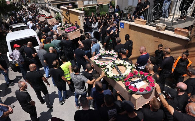 Des personnes en deuil transportent les cercueils des victimes d'une attaque à la roquette iranienne qui a détruit un immeuble de trois étages dans la ville arabe-israélienne de Tamra, dans le nord du pays, tuant quatre femmes, lors d'un enterrement à Tamra le 17 juin 2025. (Crédit : AHMAD GHARABLI / AFP)