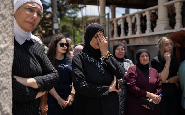 Des personnes en deuil assistent aux funérailles des victimes d'une attaque à la roquette iranienne qui a détruit un immeuble de trois étages dans la ville arabe-israélienne de Tamra, dans le nord du pays, tuant quatre femmes, à Tamra, le 17 juin 2025. (Crédit : MAYA LEVIN / AFP)