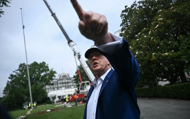 Le président américain Donald Trump s'adressant à la presse alors que des ouvriers installent un grand mât sur la pelouse sud de la Maison Blanche, à Washington, le 18 juin 2025. (Crédit : Brendan Smialowski/AFP) Le président américain Donald Trump s'adressant à la presse alors que des ouvriers installent un grand mât sur la pelouse sud de la Maison Blanche, à Washington, le 18 juin 2025. (Crédit : Brendan Smialowski/AFP)