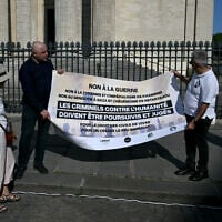 Des manifestants tiennent une banderole sur laquelle on peut lire "Non à la guerre, non à la tyrannie et à l'impérialisme de Khamenei, non au génocide de Gaza et à l'hégémonie de Netanyahu, les criminels contre l'humanité doivent être poursuivis et jugés, pour le droit des civils à vivre, pour un cessez-le-feu immédiat" alors qu'ils participent à une manifestation organisée par l'association "Iran justice" pour dénoncer le conflit en Iran, sur la place du Panthéon à Paris, le 19 juin 2025. (Crédit : Martin LELIEVRE / AFP)