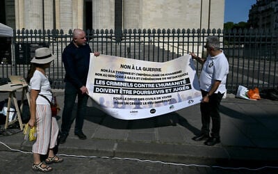 Des manifestants tiennent une banderole sur laquelle on peut lire "Non à la guerre, non à la tyrannie et à l'impérialisme de Khamenei, non au génocide de Gaza et à l'hégémonie de Netanyahu, les criminels contre l'humanité doivent être poursuivis et jugés, pour le droit des civils à vivre, pour un cessez-le-feu immédiat" alors qu'ils participent à une manifestation organisée par l'association "Iran justice" pour dénoncer le conflit en Iran, sur la place du Panthéon à Paris, le 19 juin 2025. (Crédit : Martin LELIEVRE / AFP)