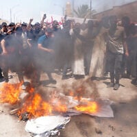 Des partisans du religieux chiite irakien Moqtada al-Sadr brûlant le drapeau israélien après la prière du vendredi pour protester contre les frappes israéliennes sur l'Iran dans la ville sainte de Najaf, le 20 juin 2025. (Crédit : Qassem al-Kaabi/AFP)