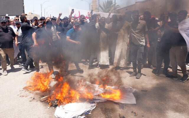 Des partisans du religieux chiite irakien Moqtada al-Sadr brûlant le drapeau israélien après la prière du vendredi pour protester contre les frappes israéliennes sur l'Iran dans la ville sainte de Najaf, le 20 juin 2025. (Crédit : Qassem al-Kaabi/AFP)
