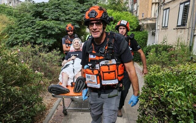 Les premiers secours israéliens évacuant une femme blessée à la suite d'une frappe iranienne sur un immeuble résidentiel, à Tel Aviv, le 22 juin 2025. (Crédit : Ahmad Gharabli/AFP) Les premiers secours israéliens évacuant une femme blessée à la suite d'une frappe iranienne sur un immeuble résidentiel, à Tel Aviv, le 22 juin 2025. (Crédit : Ahmad Gharabli/AFP)