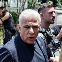 Le chef de l'opposition Yaïr Lapid s'adressant à un journaliste lors de sa visite à Tel Aviv, après une frappe iranienne qui a touché un quartier résidentiel, le 22 juin 2025. (Crédit : Jack Guez/AFP)
