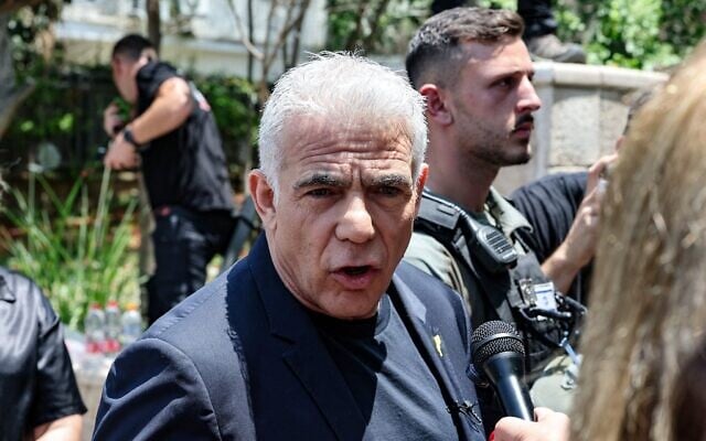 Le chef de l'opposition Yaïr Lapid s'adressant à un journaliste lors de sa visite à Tel Aviv, après une frappe iranienne qui a touché un quartier résidentiel, le 22 juin 2025. (Crédit : Jack Guez/AFP)
