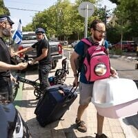 Un homme portant son chat et ses effets personnels évacuant le site d'une frappe iranienne qui a touché un quartier résidentiel, à Tel Aviv, le 22 juin 2025. (Crédit : Maya Levin/AFP)