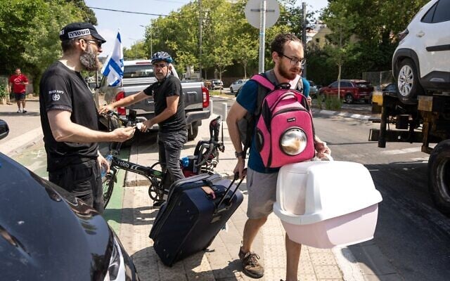 Un homme portant son chat et ses effets personnels évacuant le site d'une frappe iranienne qui a touché un quartier résidentiel, à Tel Aviv, le 22 juin 2025. (Crédit : Maya Levin/AFP)