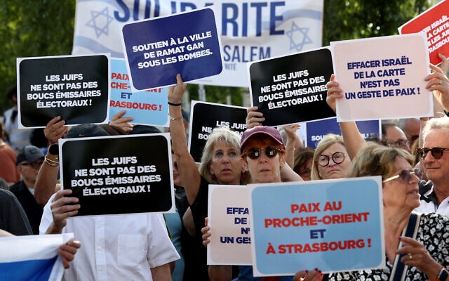 Des manifestants tiennent des pancartes devant l'hôtel de ville de Strasbourg lors d'un rassemblement organisé par le Conseil représentatif des institutions juives de France (CRIF) pour protester contre le projet de jumelage entre la ville de Strasbourg et le camp palestinien d'Aïda, à Strasbourg, dans l'est de la France, le 23 juin 2025. Le projet de jumelage de la Ville de Strasbourg avec le camp palestinien d'Aïda est soumis au vote du Conseil municipal le 23 juin 2025. (Crédit : FREDERICK FLORIN / AFP)