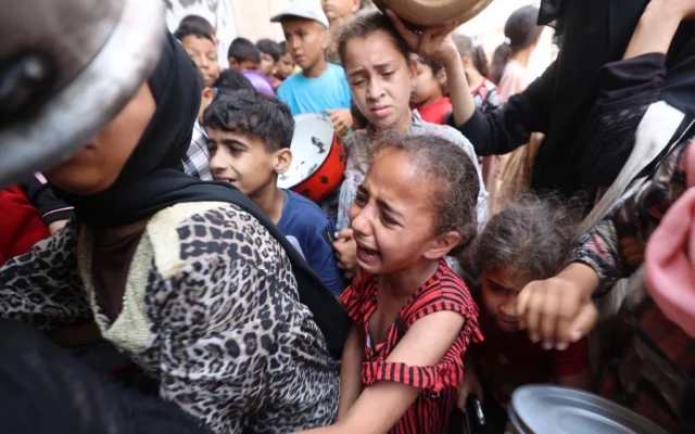 Des personnes font la queue à un point de distribution de nourriture à Nuseirat, dans le centre de la bande de Gaza, le 23 juin 2025. (Crédit : Eyad BABA / AFP)