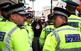 Illustration : Des policiers métropolitains se tenant devant des manifestants lors d'un rassemblement anti-Israël en soutien au groupe Palestine Action, alors que le gouvernement britannique s'apprête à l'interdire, à Trafalgar Square, dans le centre-ville de Londres, le 23 juin 2025. (Crédit : Henry Nicholls/AFP)