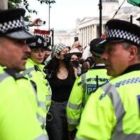 Illustration : Des policiers métropolitains se tenant devant des manifestants lors d'un rassemblement anti-Israël en soutien au groupe Palestine Action, alors que le gouvernement britannique s'apprête à l'interdire, à Trafalgar Square, dans le centre-ville de Londres, le 23 juin 2025. (Crédit : Henry Nicholls/AFP)