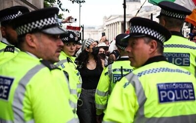 Illustration : Des policiers métropolitains se tenant devant des manifestants lors d'un rassemblement anti-Israël en soutien au groupe Palestine Action, alors que le gouvernement britannique s'apprête à l'interdire, à Trafalgar Square, dans le centre-ville de Londres, le 23 juin 2025. (Crédit : Henry Nicholls/AFP)