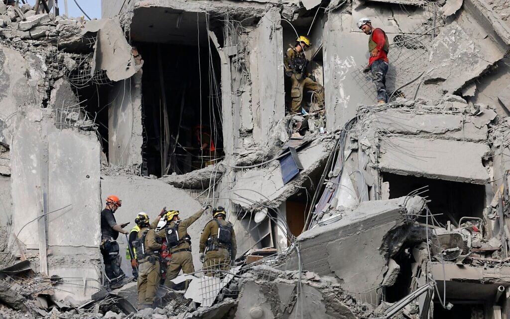 Des soldats israéliens et des équipes de secours recherchant des survivants parmi les décombres d'immeubles résidentiels détruits par une frappe de missile iranien qui a fait plusieurs morts, à Beer Sheva, en Israël, le 24 juin 2025. (Crédit : John Wessels/AFP)